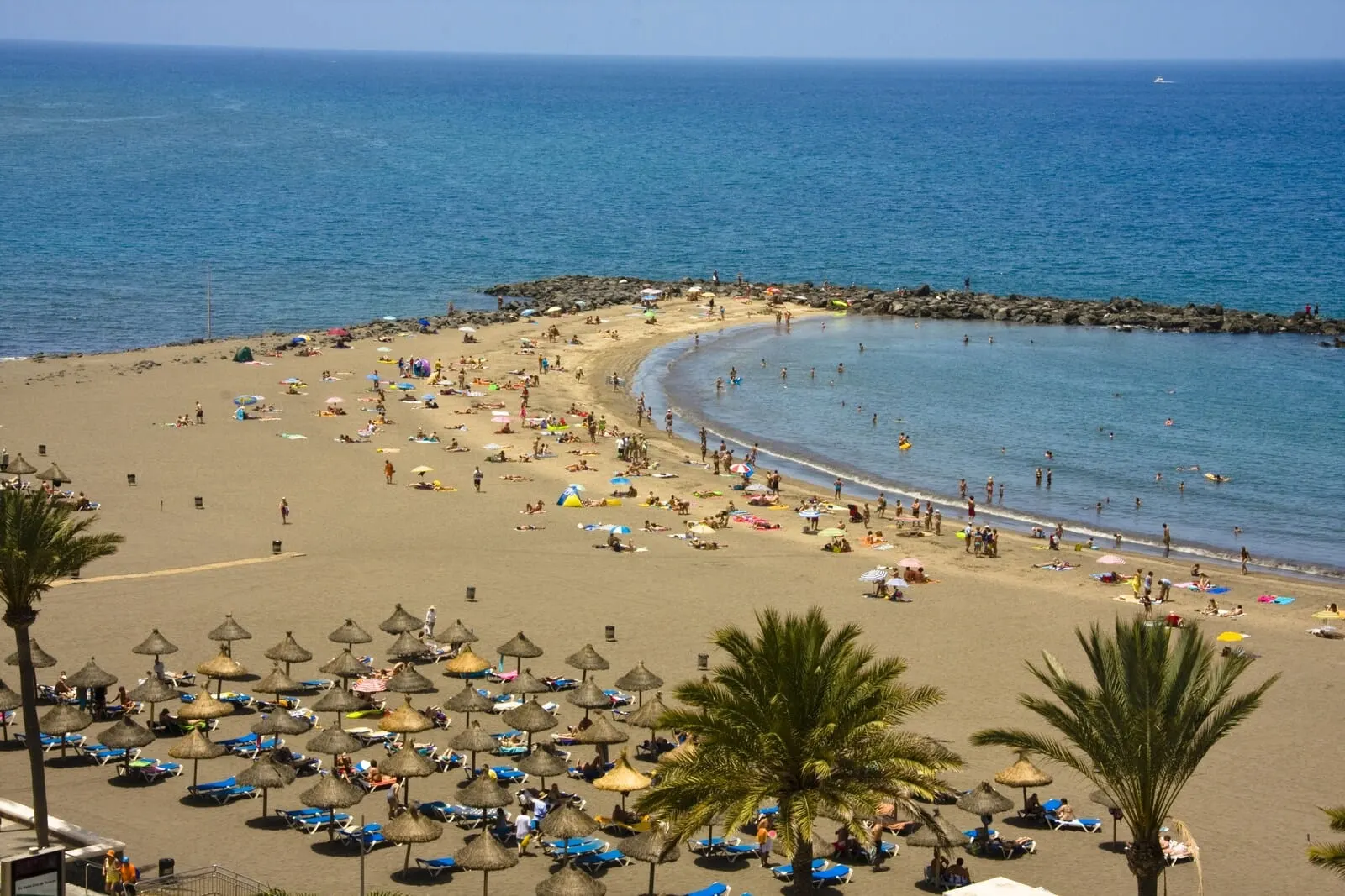 Ona Palm Beach: A beach with umbrellas, sun loungers, and people