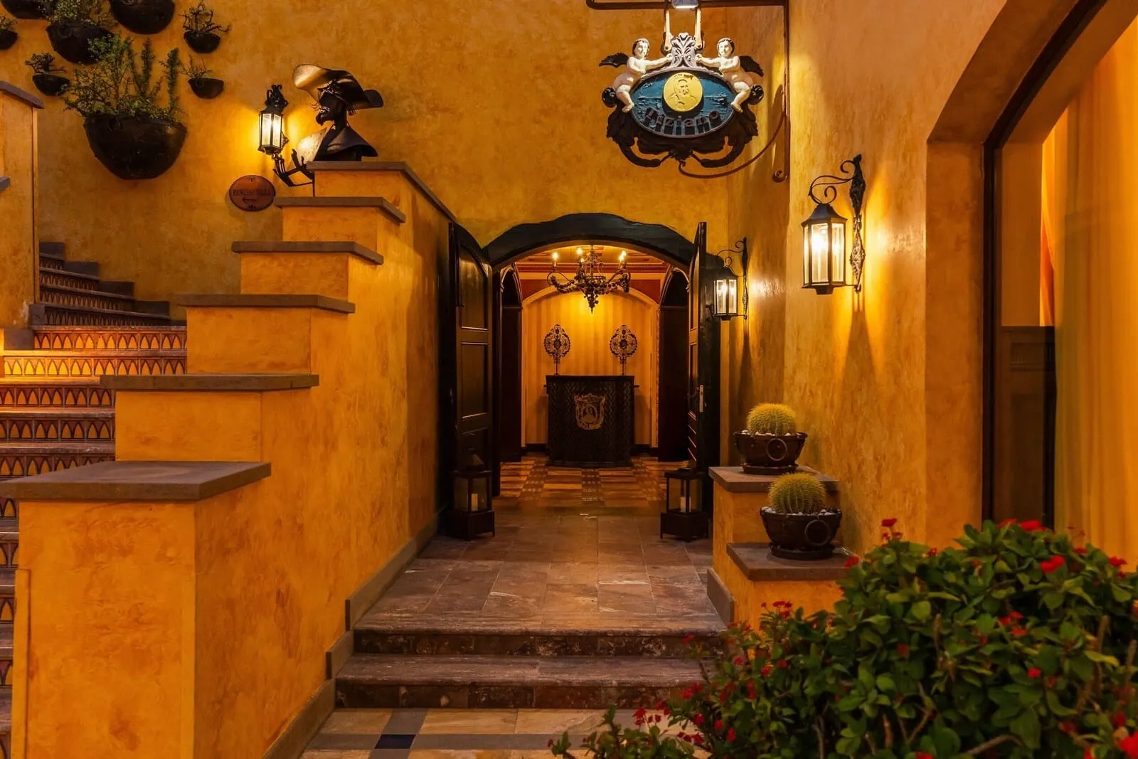 Europe Villa Cortés: A grand staircase leading to a room with a chandelier, wall sconces, and potted plants