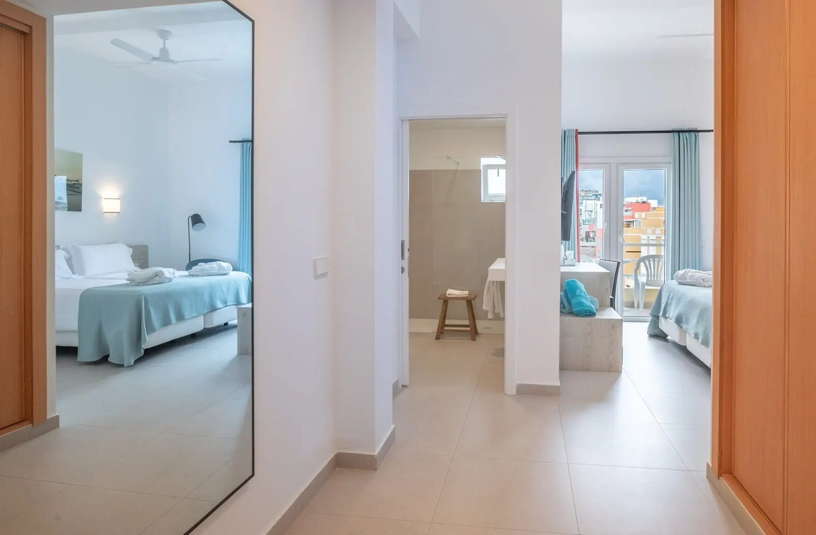 Médano Hotel: A hotel room with a bed, a small stool, and a window with curtains