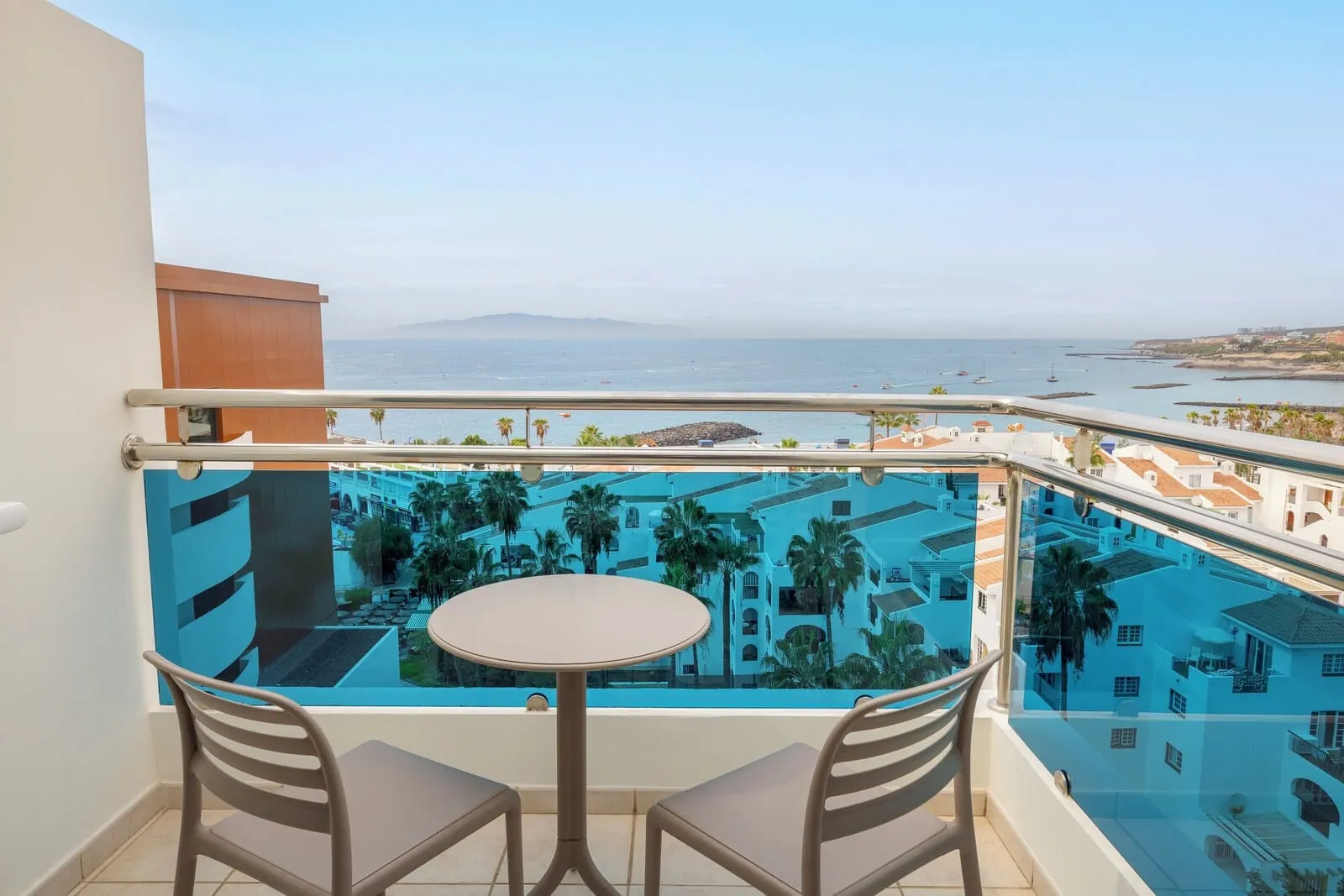 AluaSoul Costa Adeje: A balcony with a glass railing, two chairs, and a small round table