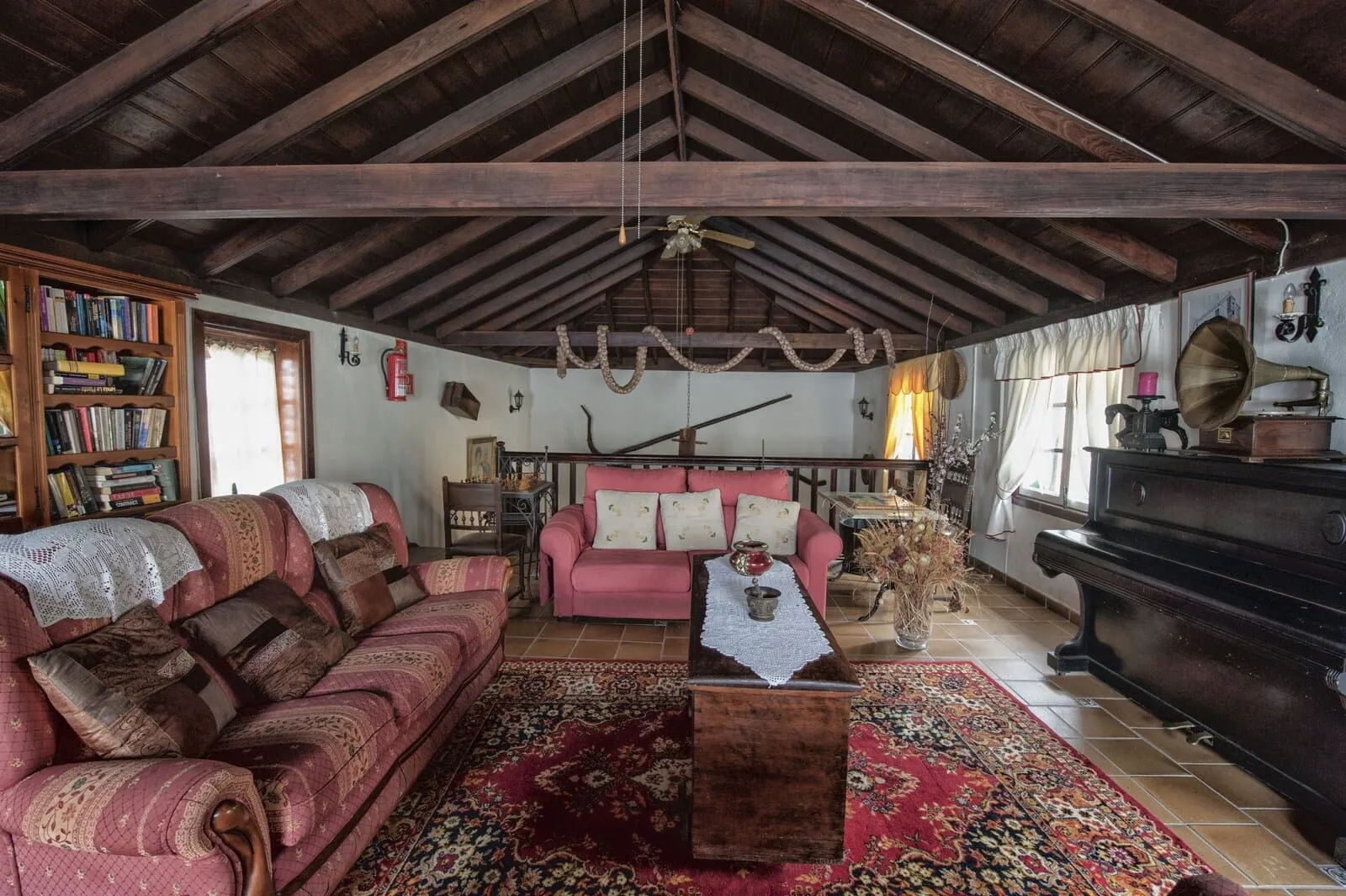 Hotel Rural Senderos de Abona: A cozy living room with a wooden ceiling, a red sofa, a coffee table, and a piano