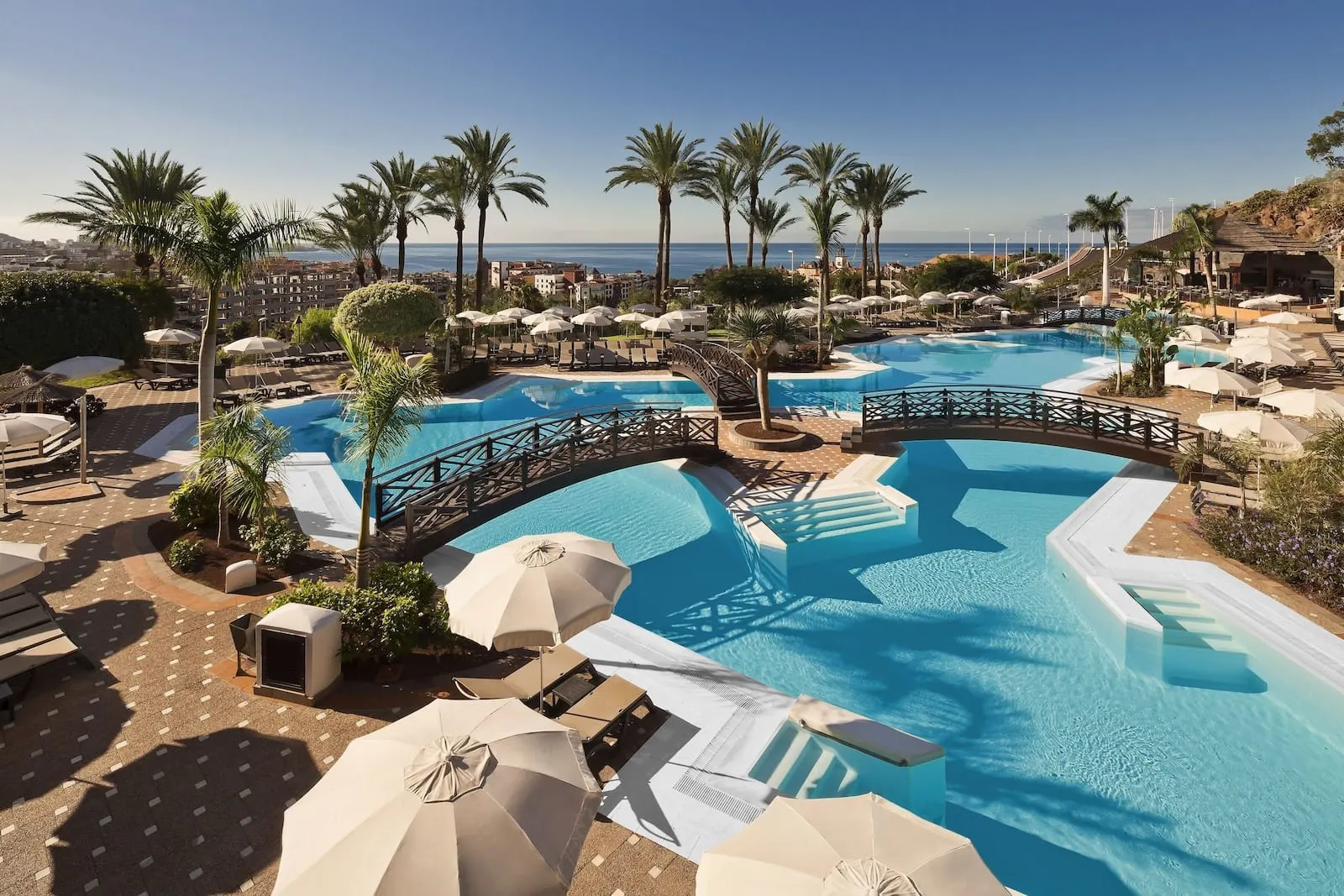 Meliá Jardines del Teide: A resort pool area with multiple swimming pools, lounge chairs, umbrellas