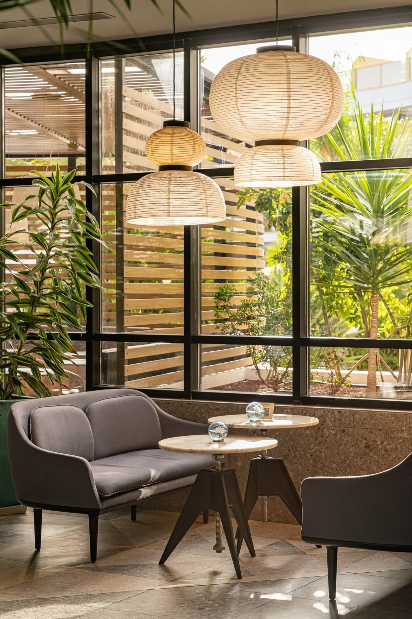 Sir Anthony: A modern interior with a sofa, two chairs, a round table, and hanging paper lanterns