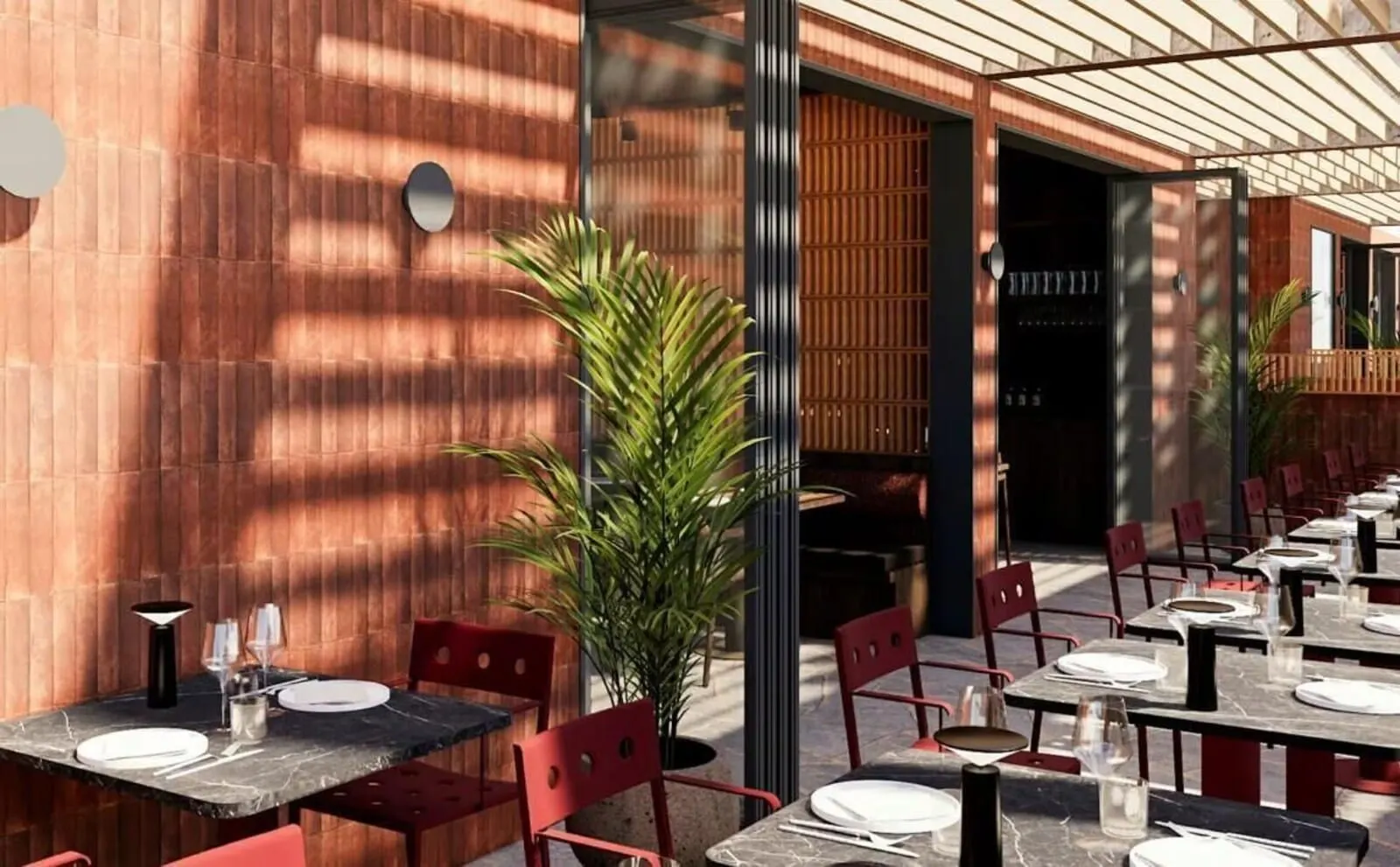 Coral California: An outdoor dining area with tables and chairs, a potted plant, and a wooden wall