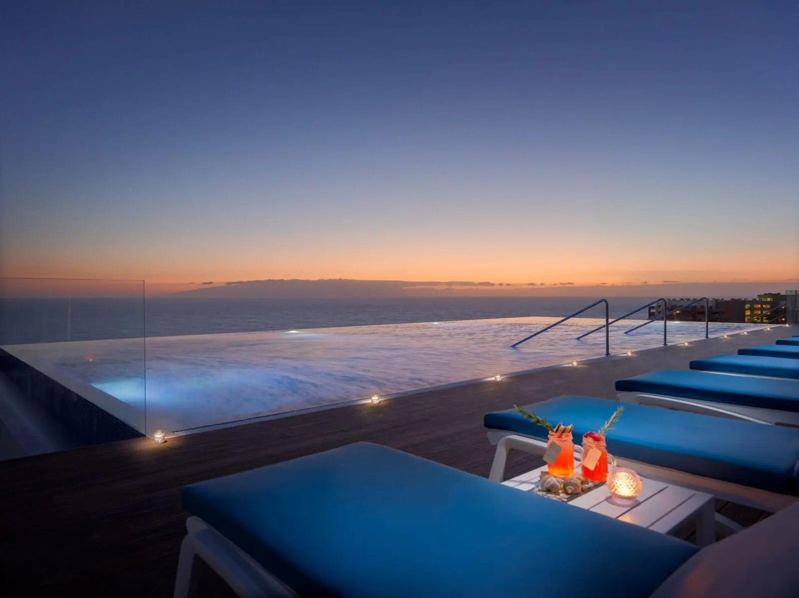 H10 Atlantic Sunset: An infinity pool with a sunset view, blue lounge chairs