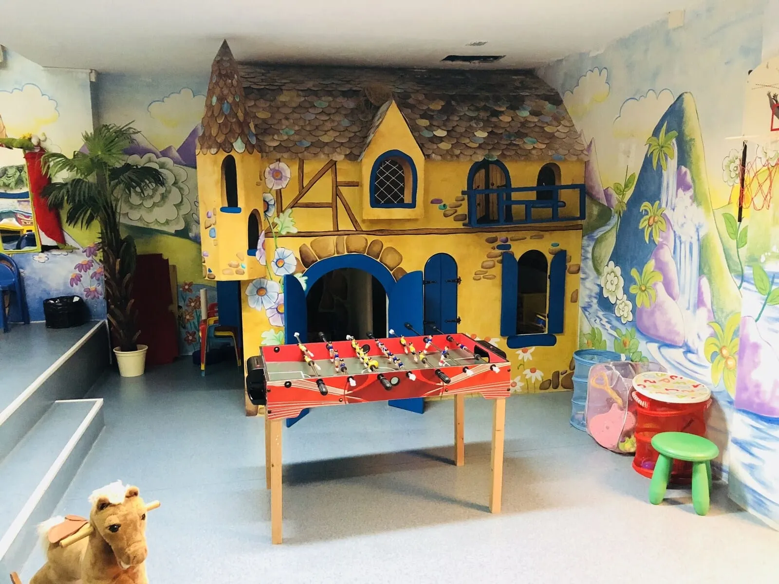 Regency Torviscas Apartments & Suites: A room with a foosball table, a small horse figure, and a mural of a colorful house