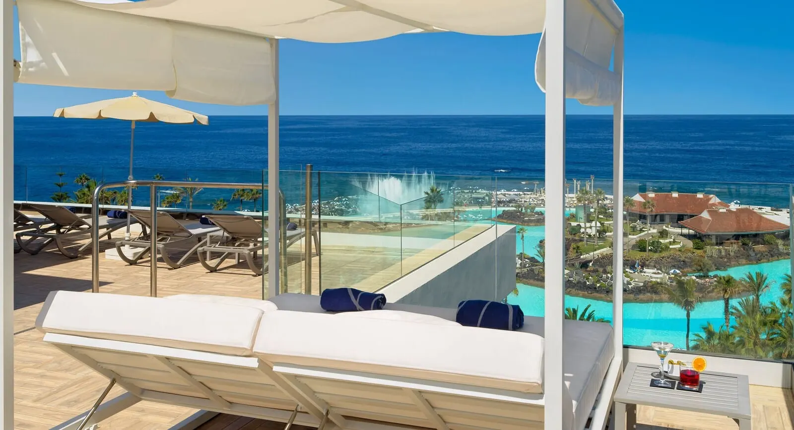 H10 Tenerife Playa: A balcony with a glass barrier overlooking a pool and the ocean