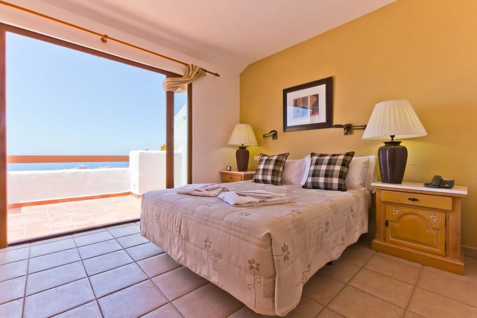 Ona Beverly Hills Suites: A hotel room with a bed, two bedside tables with lamps, a picture on the wall