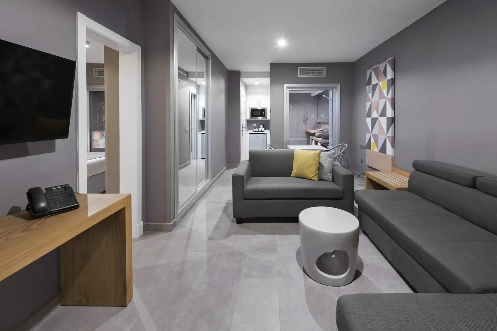 Atlantic Mirage Suites & Spa: A modern living room with grey sofas, a coffee table, and a TV on a wooden stand