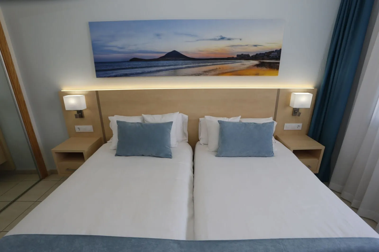 Hotel Andorra: A hotel room with two beds, a large painting of a beach scene, and bedside lamps