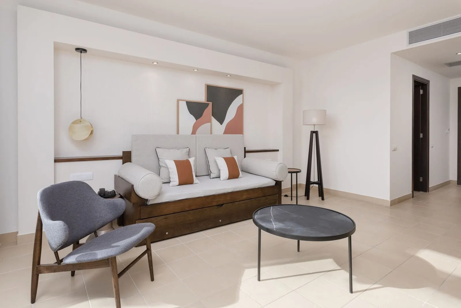 Barceló Tenerife: A modern bedroom with a sofa bed, a chair, a small table, and abstract wall art