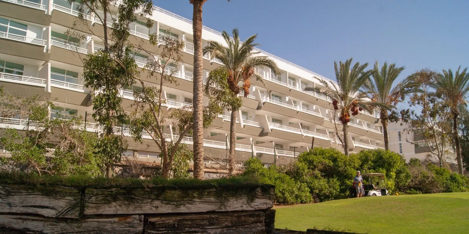 Gara Suites Golf & Spa: A multi-story hotel with balconies, palm trees, and a golf cart