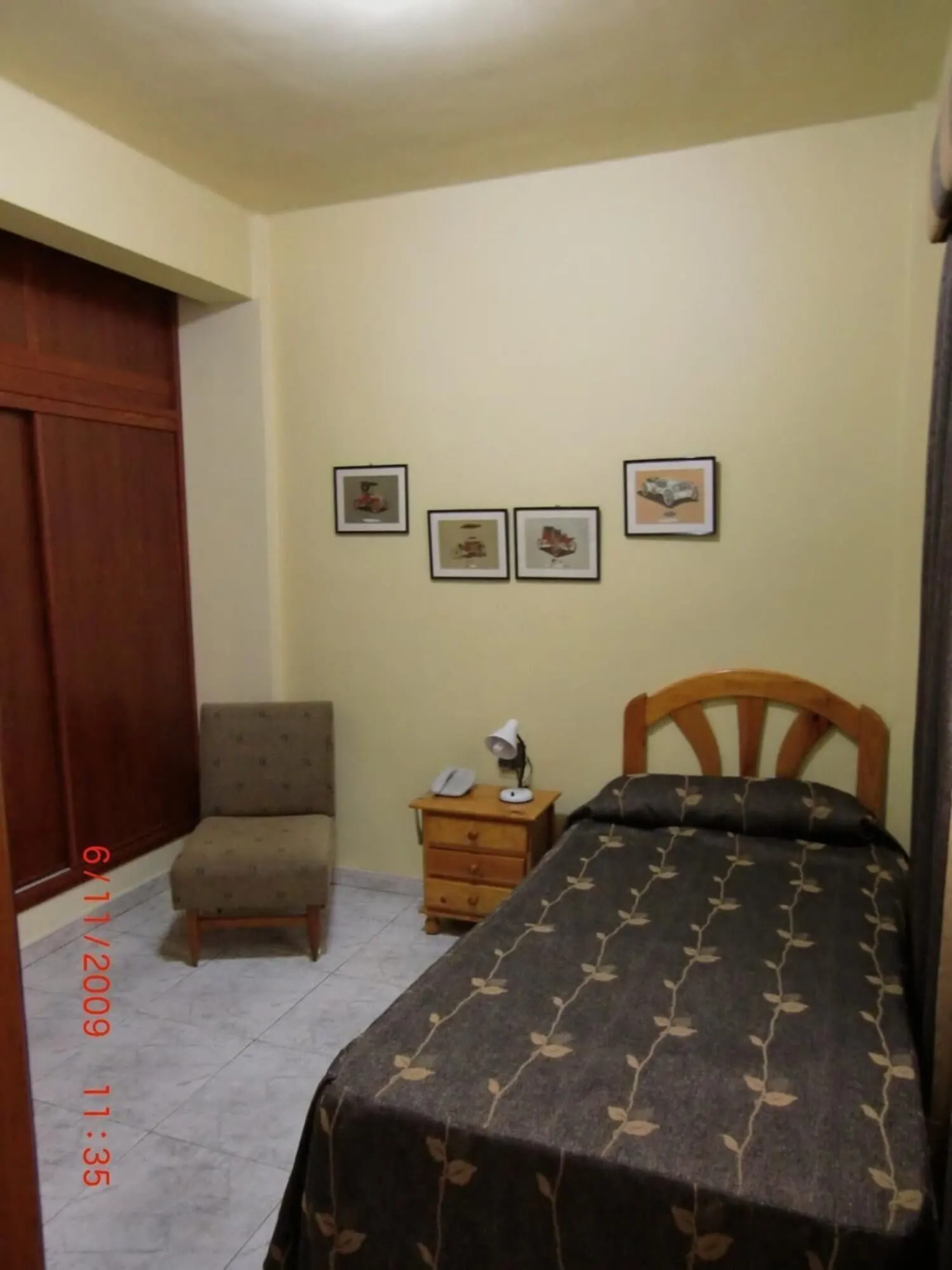 Hotel Tanausú: A bedroom with a bed, a chair, a nightstand, and three framed pictures on the wall