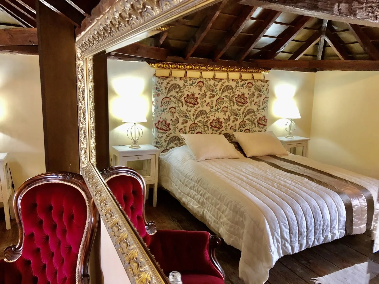 Hotel Rural Vilaflor: A bedroom with a large bed, two bedside tables, a mirror, and a red chair