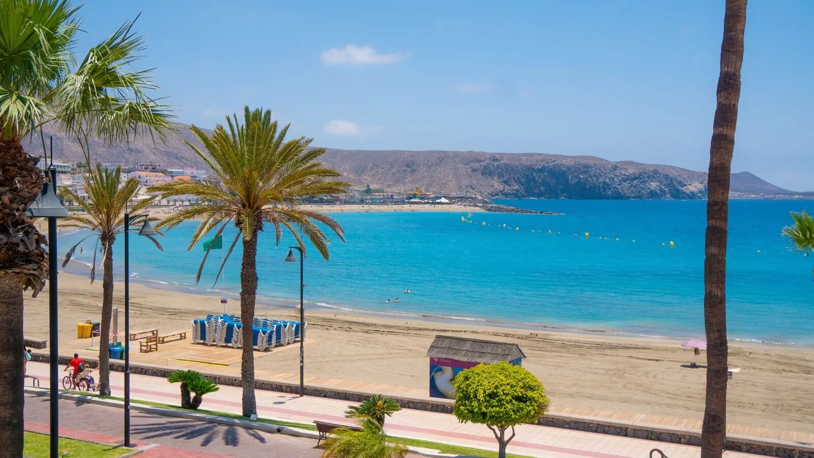 Coral Compostela Beach: A beach with clear blue water, palm trees, and a mountain in the background