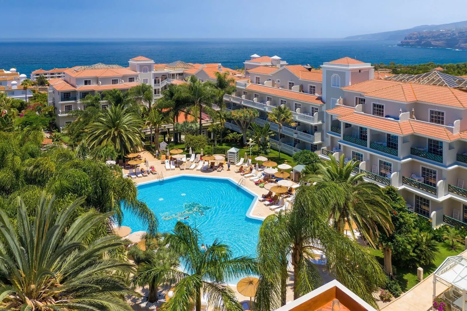 Hotel Riu Garoé: A resort with a central swimming pool surrounded by palm trees and sun loungers