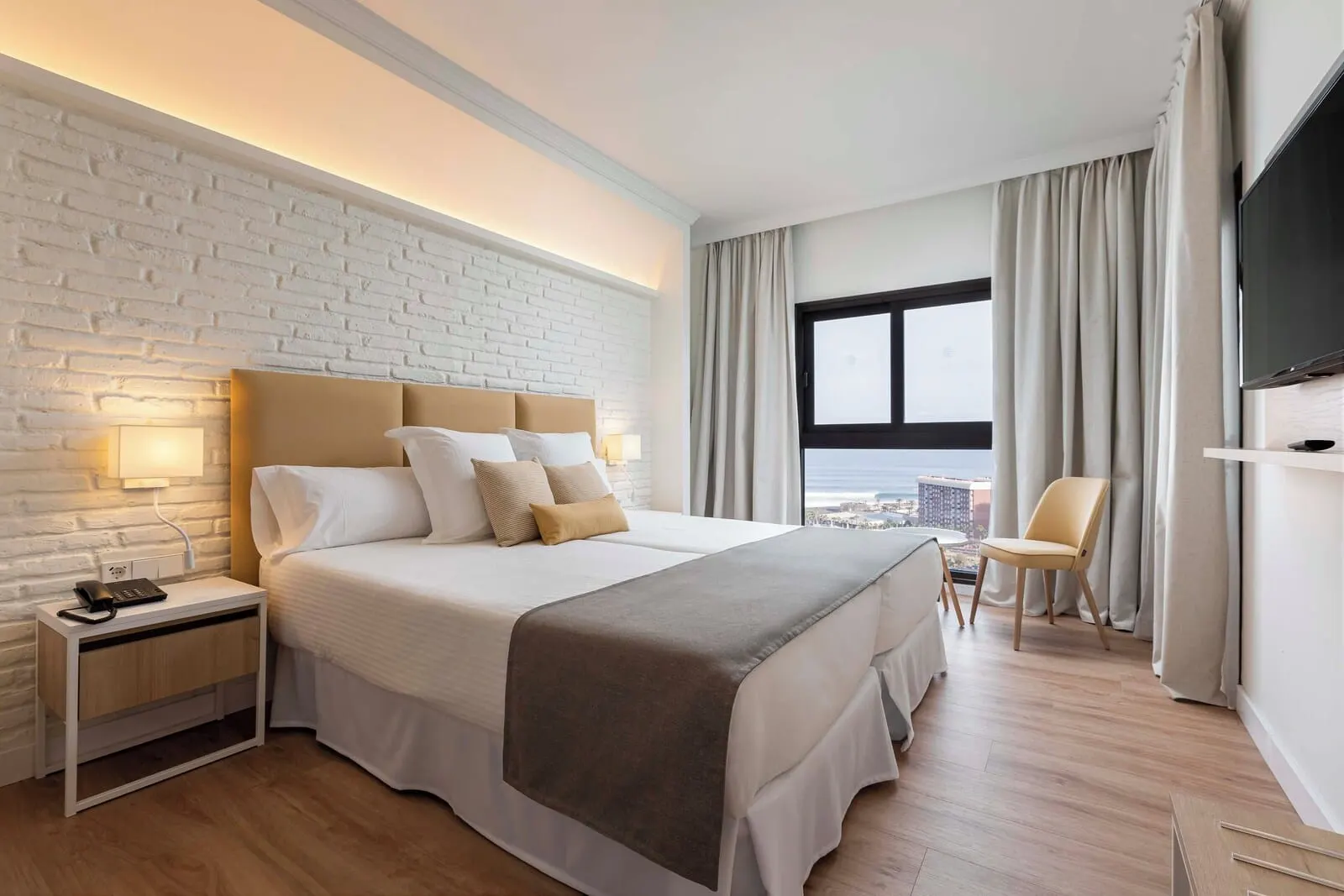 AluaSoul Orotava Valley: A modern hotel room with a large bed, a nightstand, a TV, and a view of the city