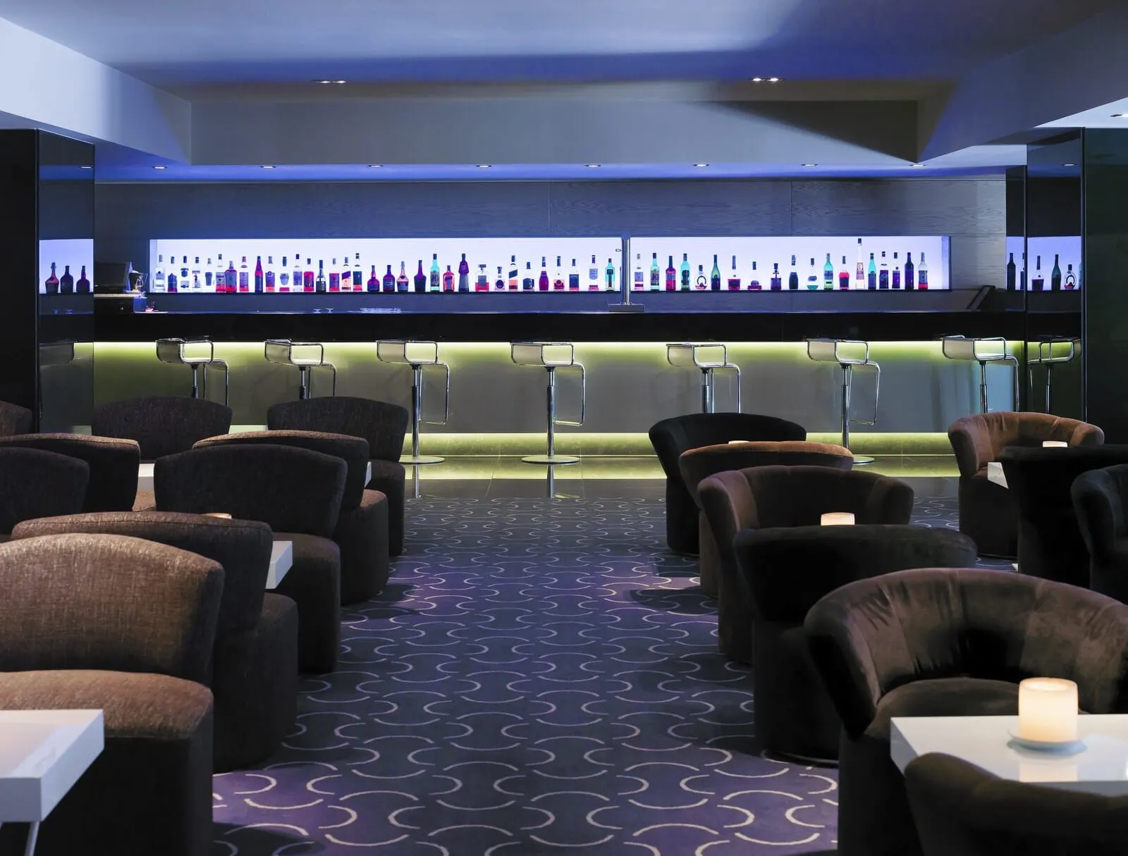 H10 Gran Tinerfe: A bar area with multiple stools and a display of various liquor bottles