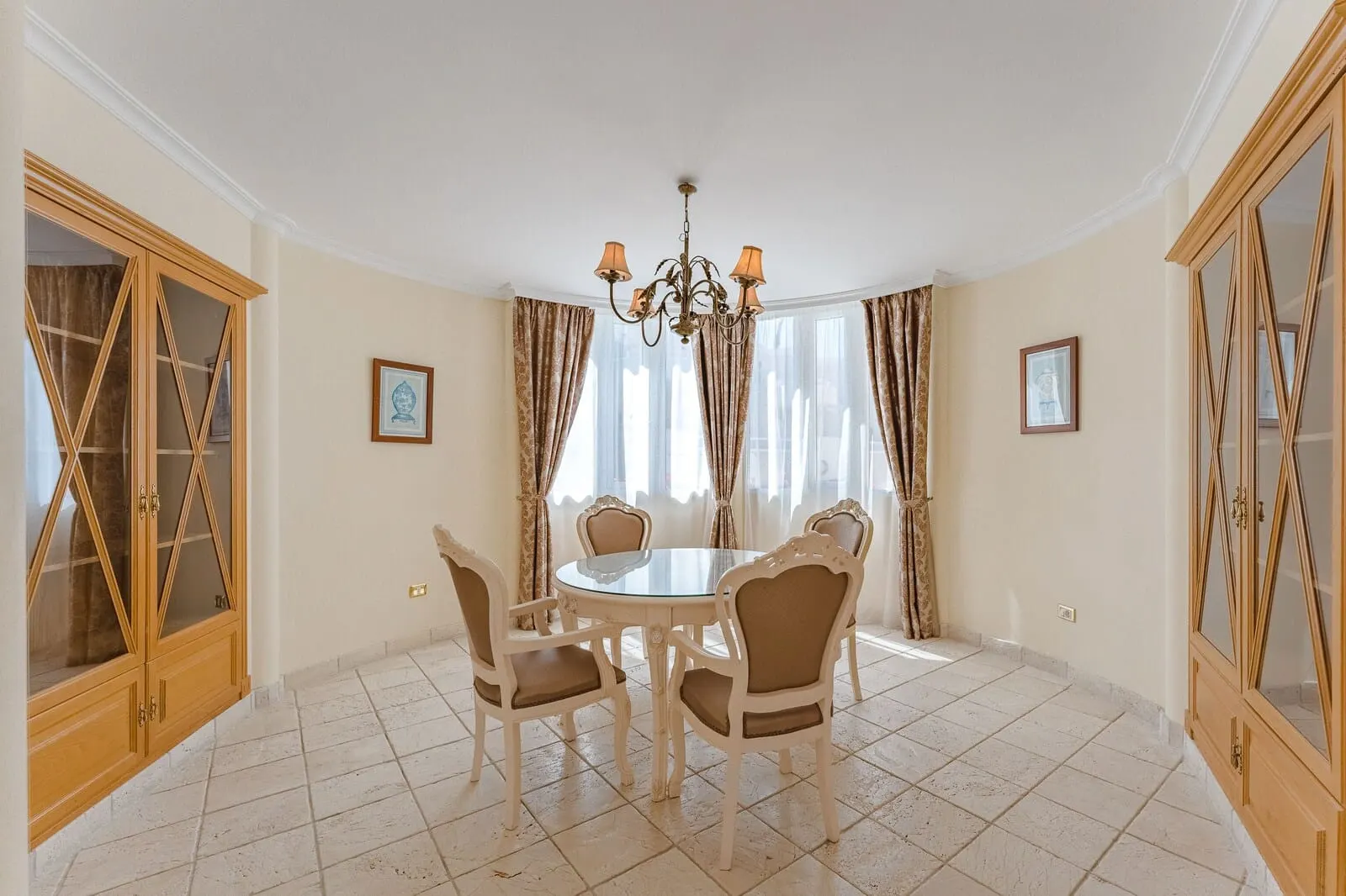 Flamingo Suites Boutique Hotel: A dining room with a round table, four chairs, a chandelier, and wooden cabinets