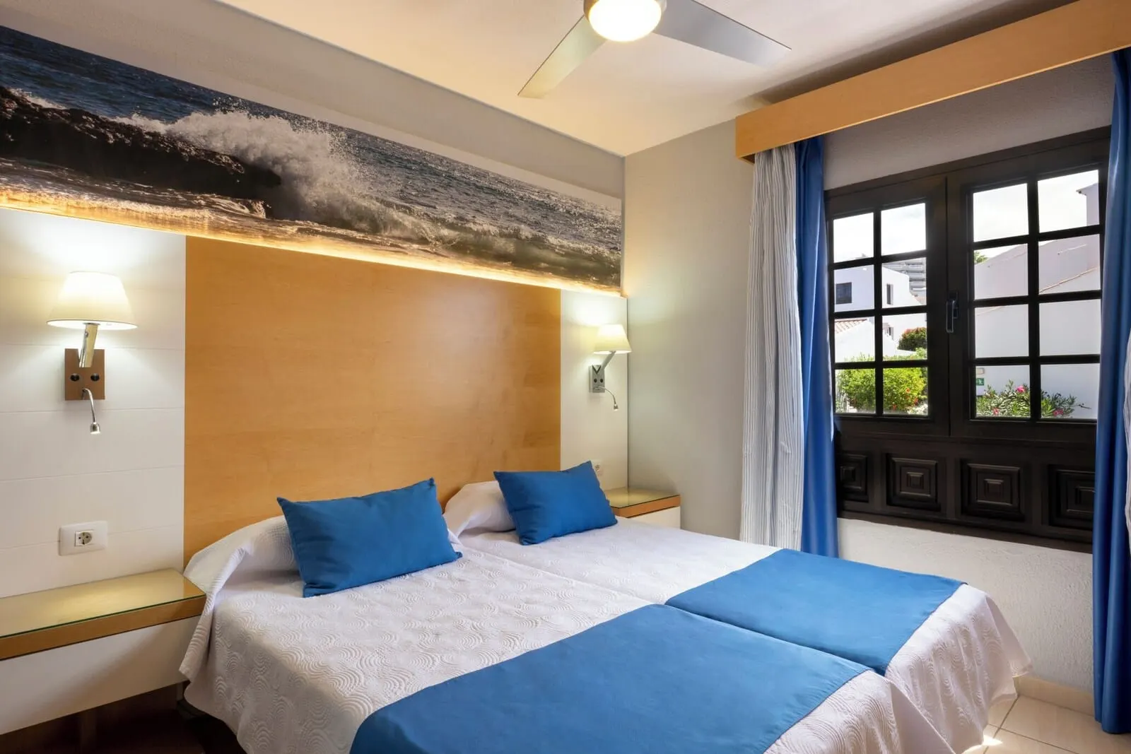 Ona Las Rosas: A hotel room with a bed, two bedside lamps, a window with curtains