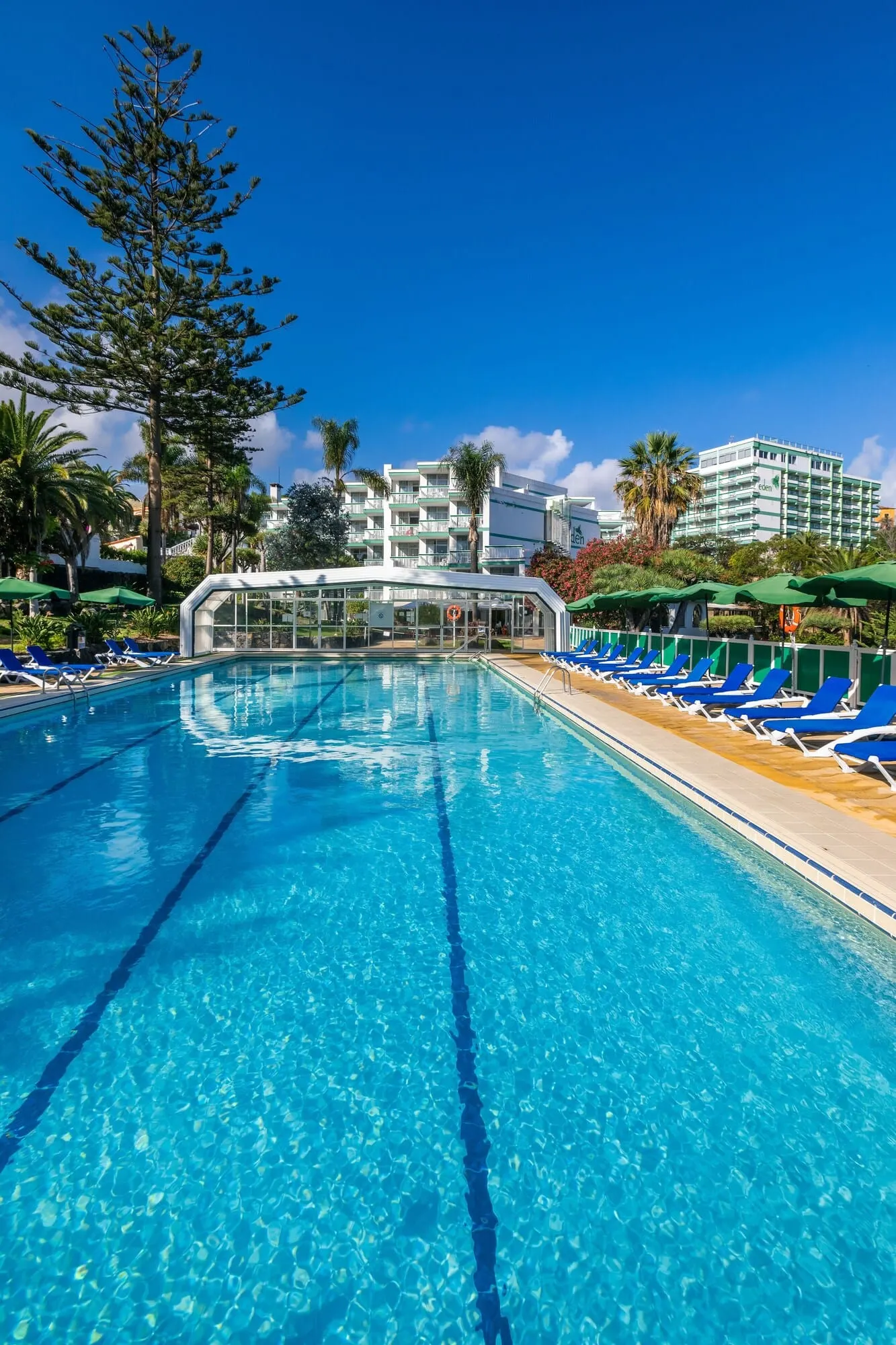 Parque Vacacional Eden: A clear blue swimming pool with lounge chairs and a glass-enclosed area