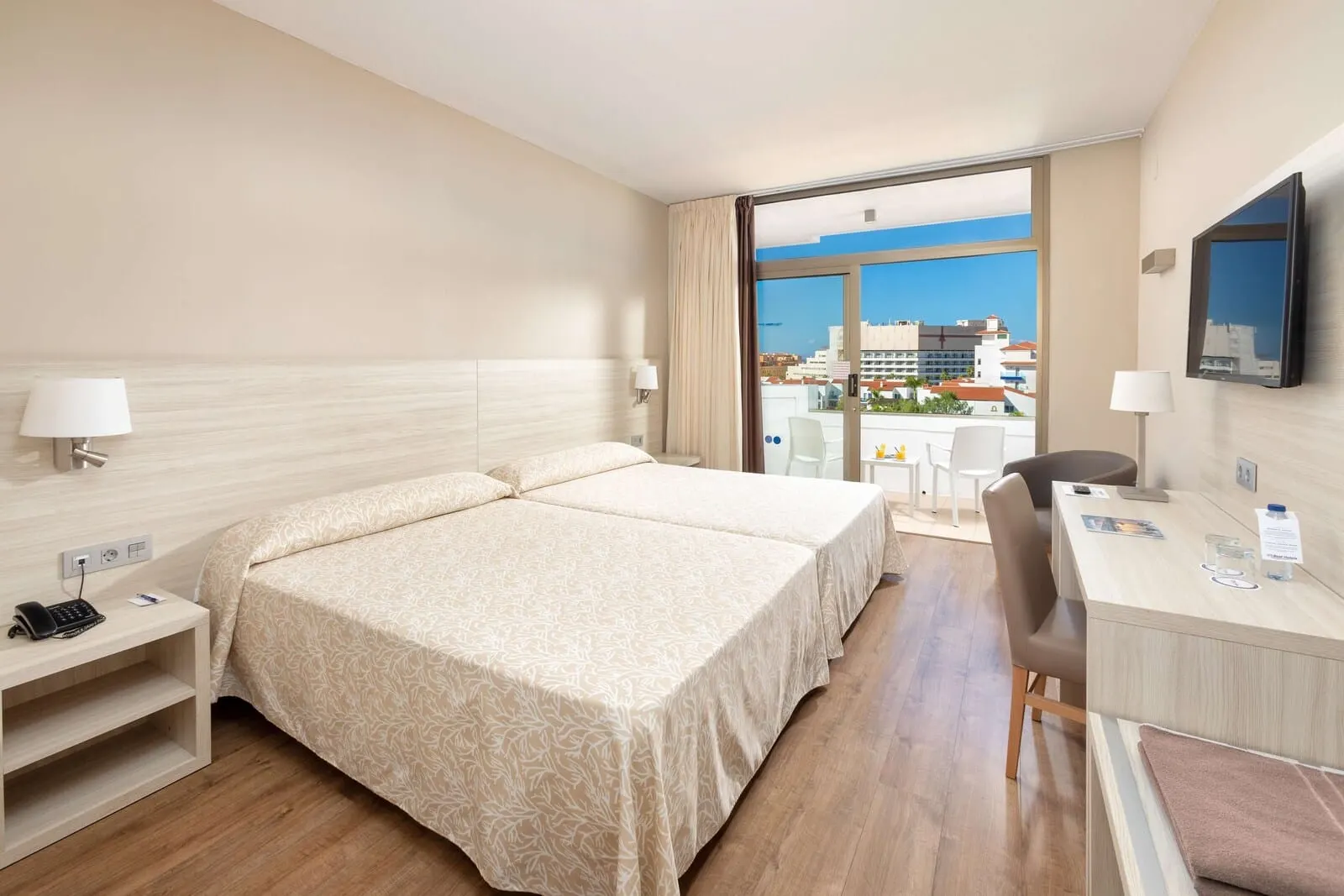 Best Tenerife: A hotel room with a large bed, a desk, a chair, and a TV
