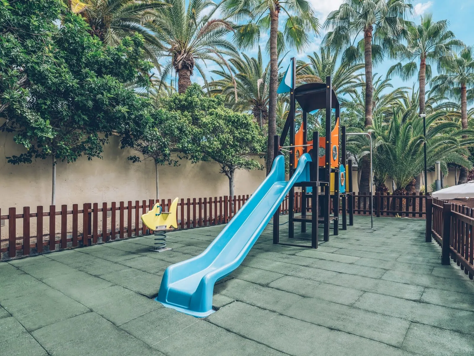Iberostar Waves Las Dalias: A playground with a blue slide and a yellow swing set