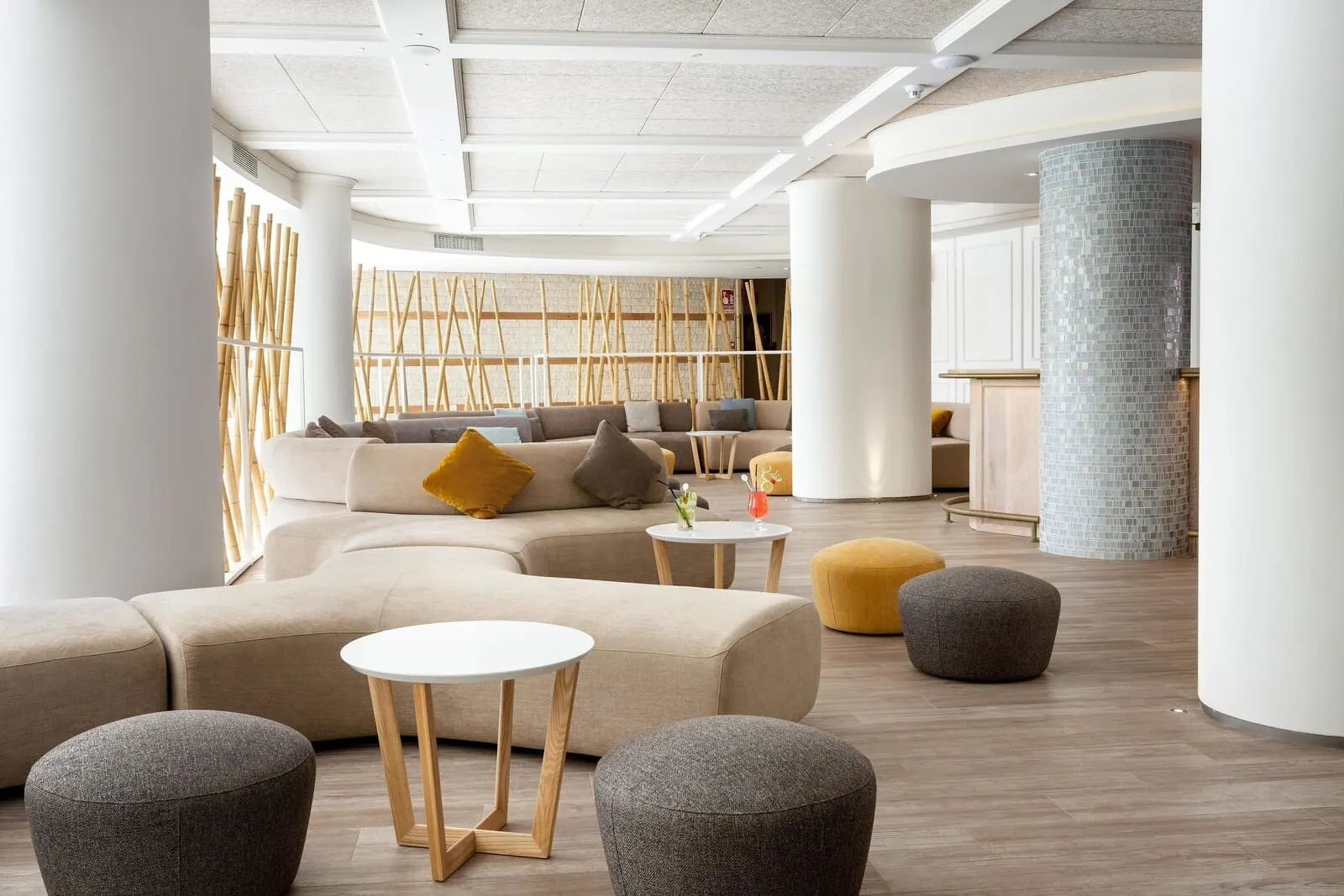 Tigotan Lovers & Friends: A modern interior with a sectional sofa, round ottomans, and a small white table