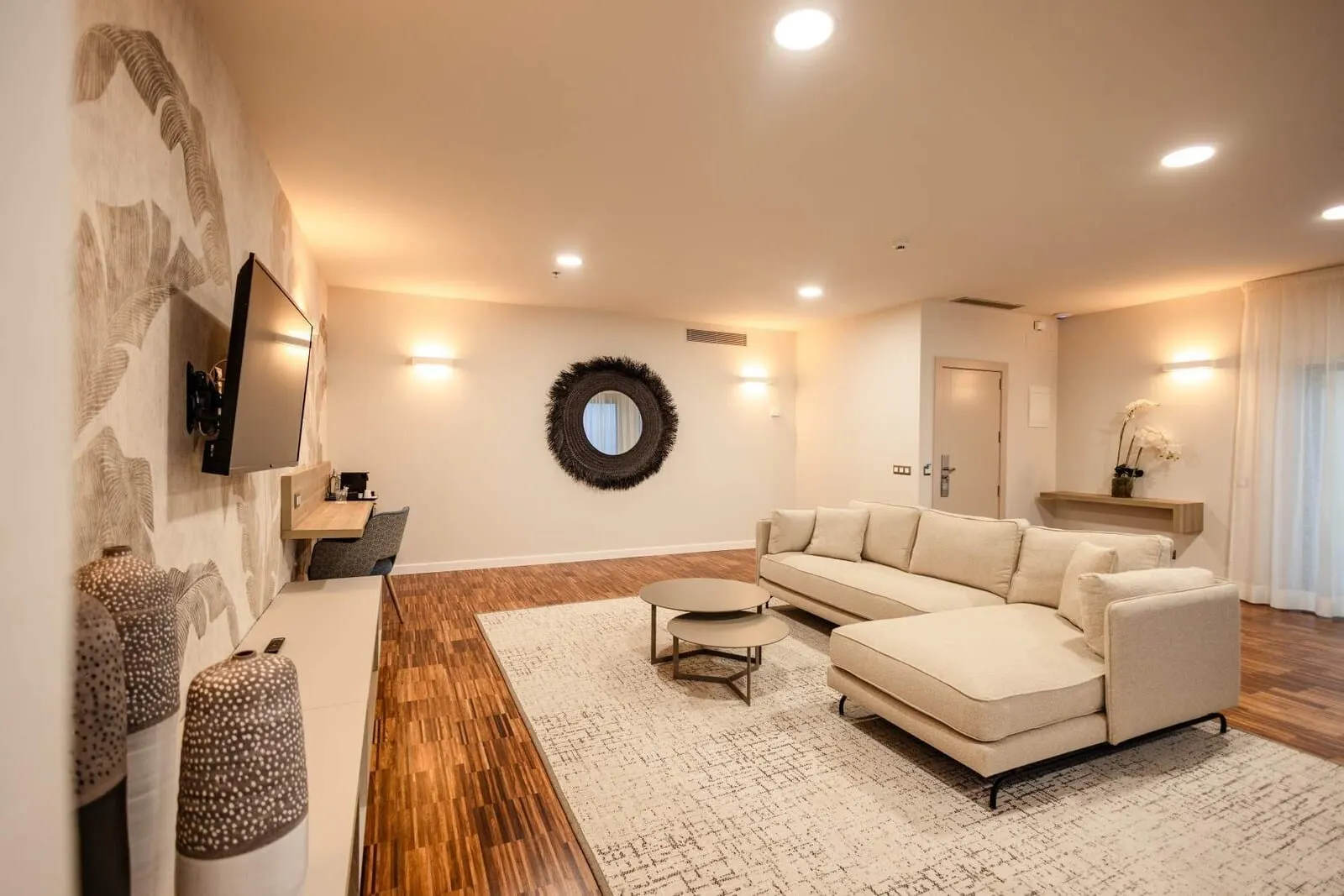 Hotel Escuela Santa Cruz: A modern living room with a sofa, a coffee table, a TV, and a decorative wall