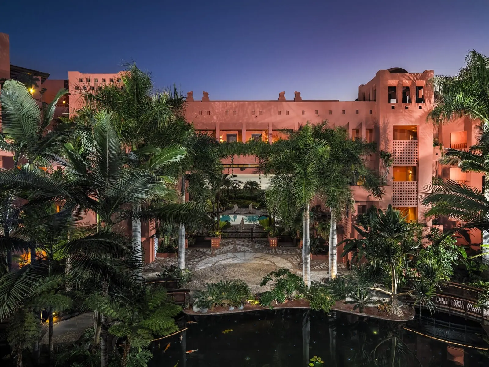 The Ritz-Carlton Tenerife, Abama: A resort with a pool, palm trees, and a large building with multiple balconies
