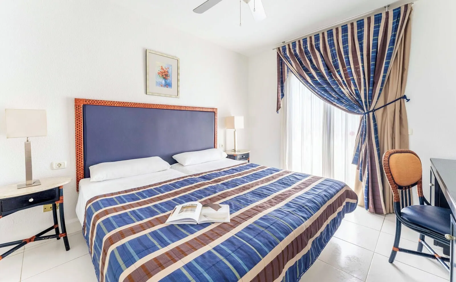 Ona Beverly Hills Heights: A hotel room with a large bed, two bedside tables, a chair, and a ceiling fan