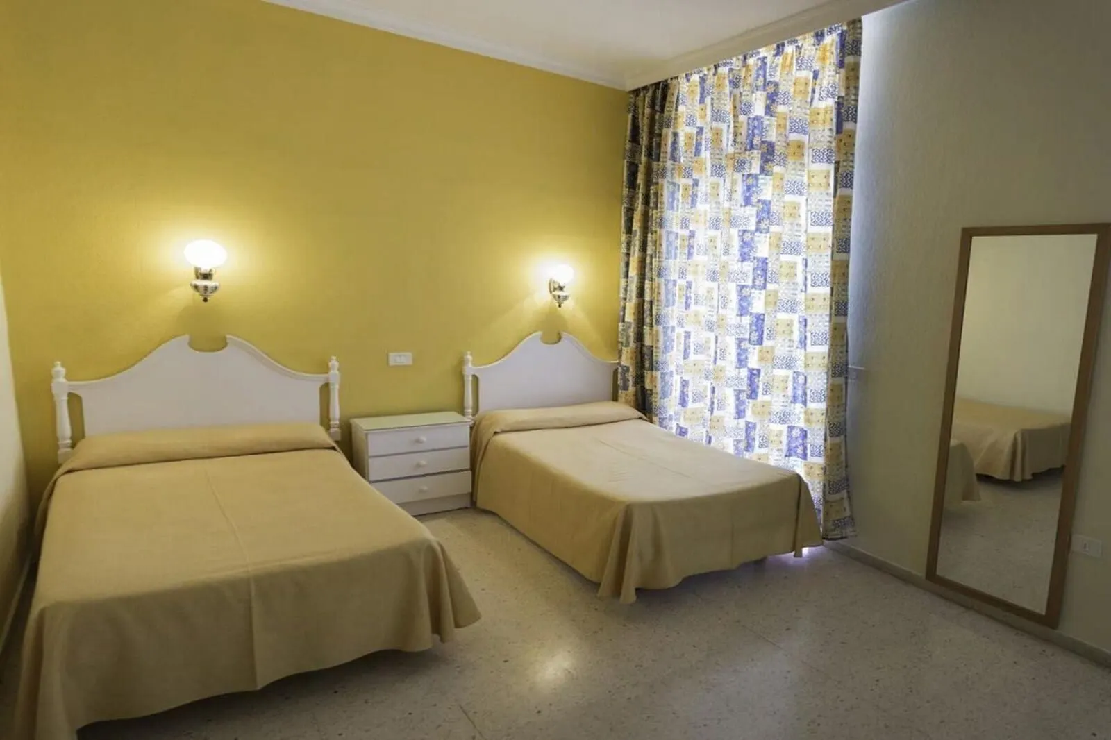 Hotel Don Cándido: A room with two single beds, a bedside table, a mirror, and a patterned curtain