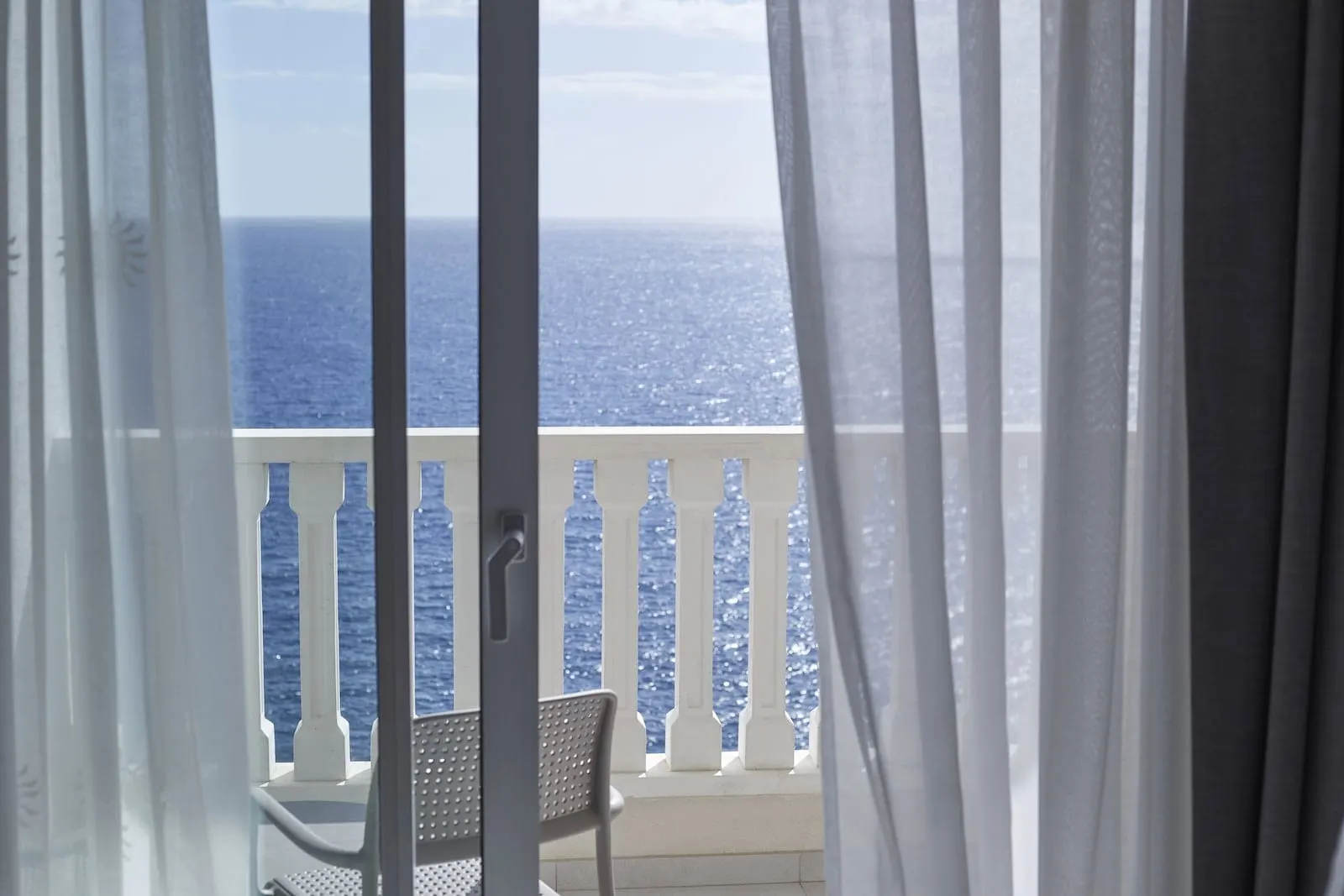 Bahia Principe Explore Fantasia: A balcony with a view of the ocean, a white chair, and white balustrades