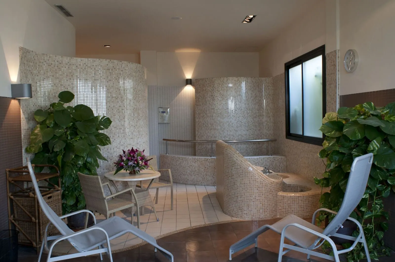 Hotel Luz del Mar: A spa area with a seating area, a small table with flowers, and a large plant