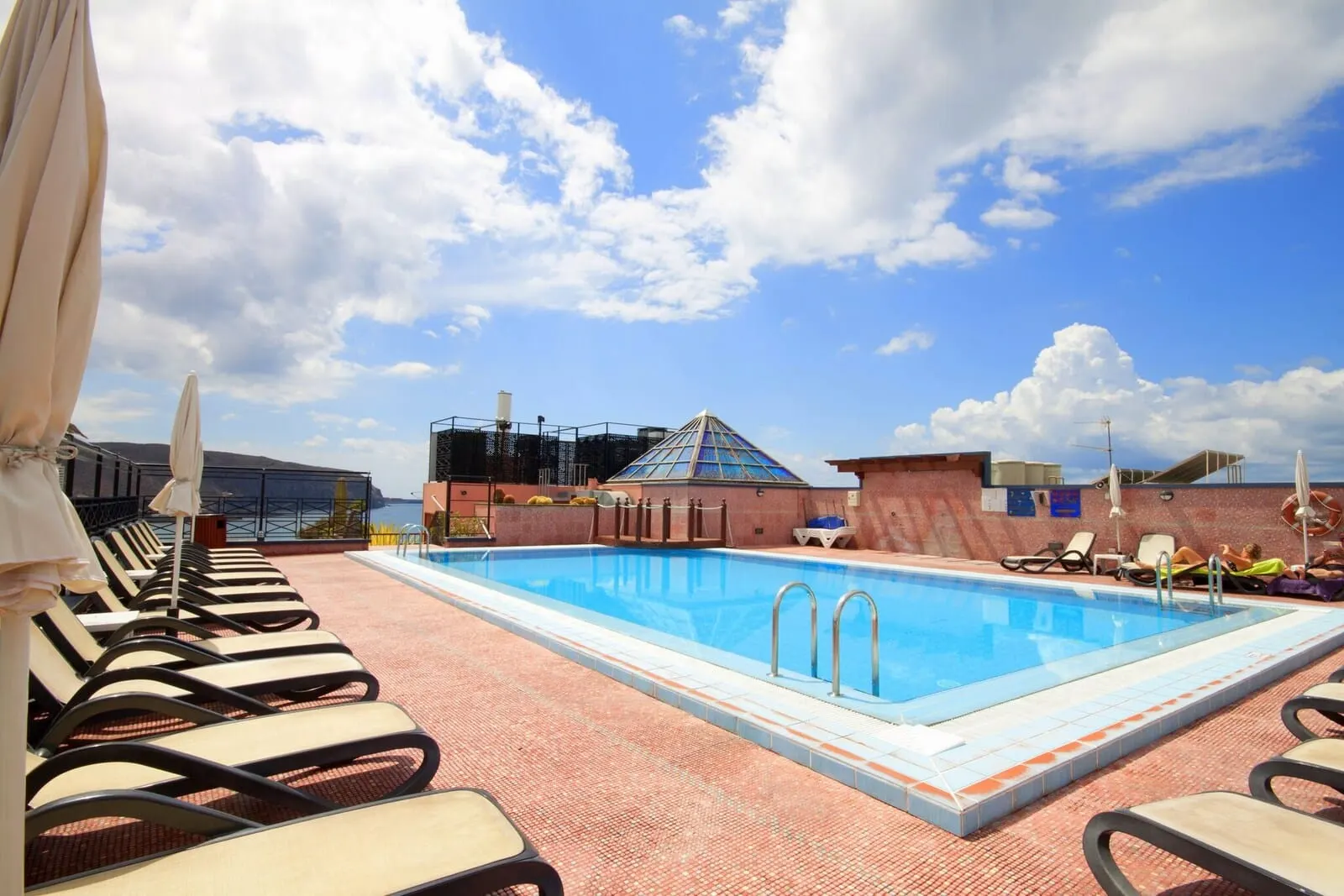 Hotel Reverón Plaza: A rooftop pool with lounge chairs and umbrellas, a glass-domed structure