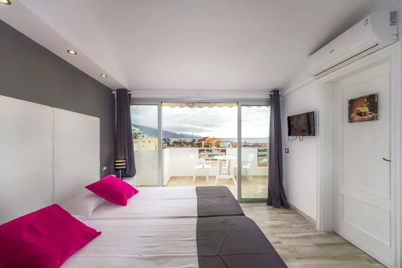 Hotel Sun Holidays: A bedroom with a bed, a TV, and a balcony with a view of the city