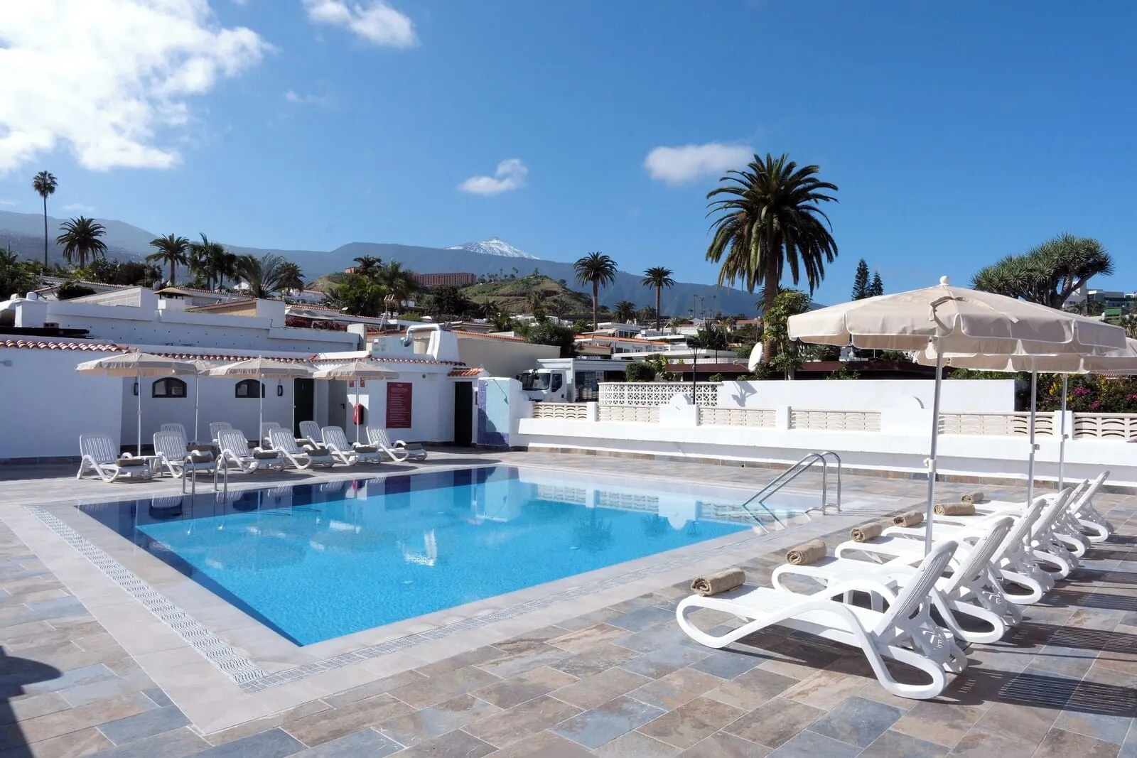 Muthu La Perla Tenerife: A swimming pool with lounge chairs and umbrellas