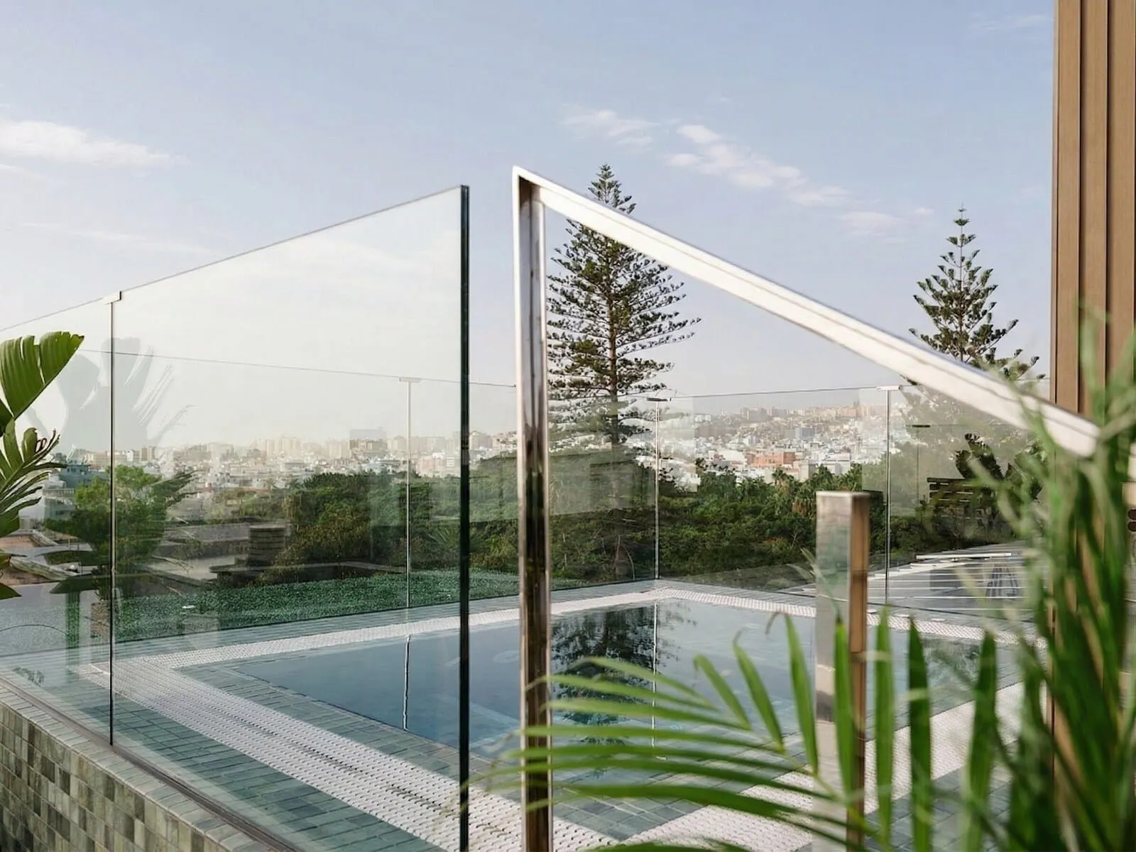 Hotel Taburiente: A modern outdoor pool area with glass railings, a clear view of the cityscape
