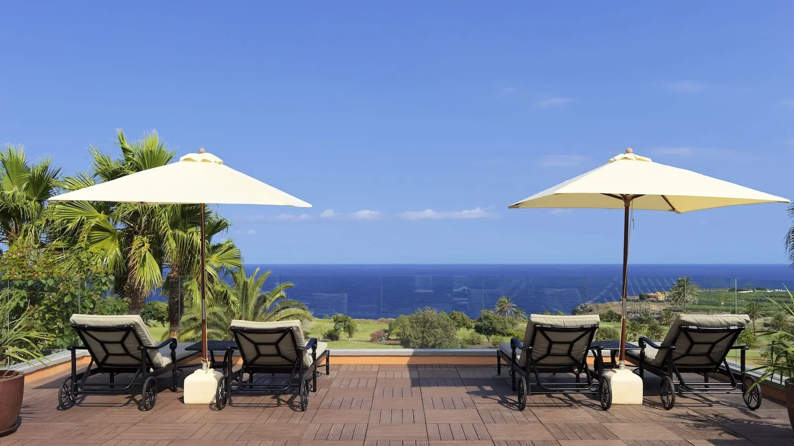 Hacienda del Conde Meliá Collection Golf & Spa: A terrace with two lounge chairs and umbrellas, overlooking a coastal view