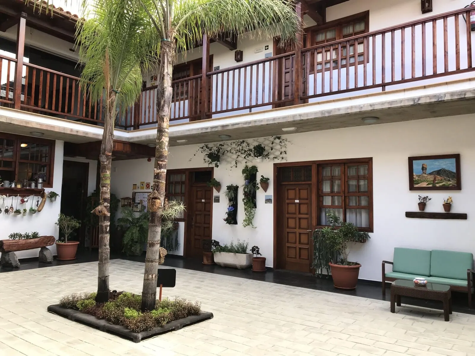 Garahotel: A courtyard with a wooden bench, potted plants, and a palm tree