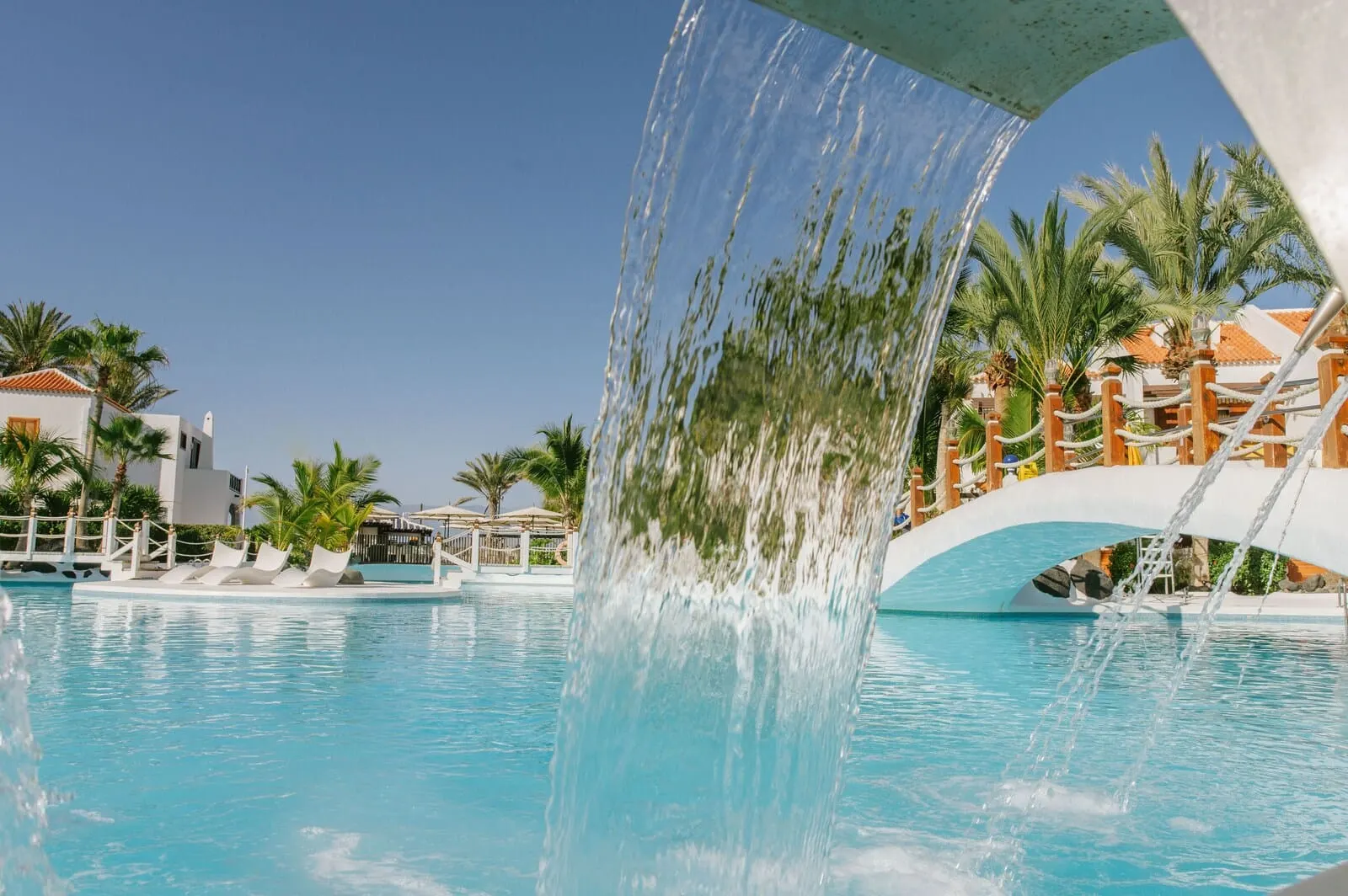 Parque Santiago III: A pool with a water feature, palm trees, and a bridge