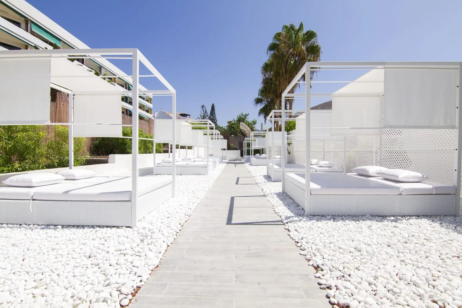 Checkin Bungalows Atlántida: A pathway leading to white outdoor seating areas with cushions