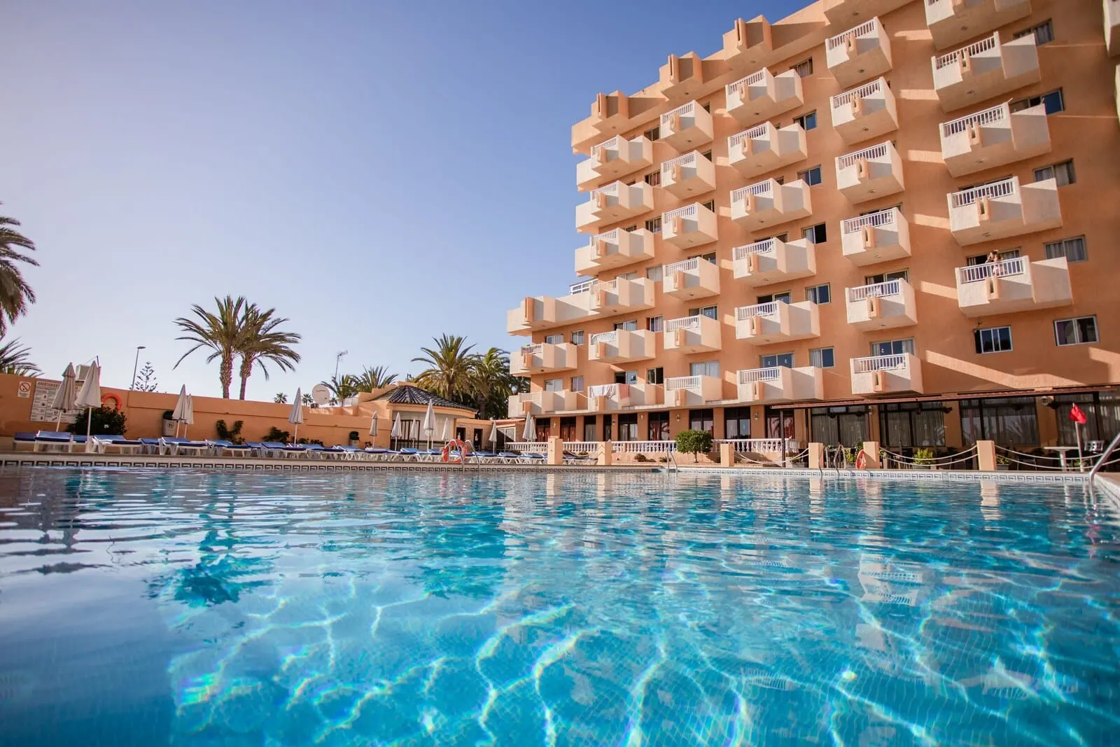 Servatur Caribe: A hotel with a pool, multiple balconies, and palm trees
