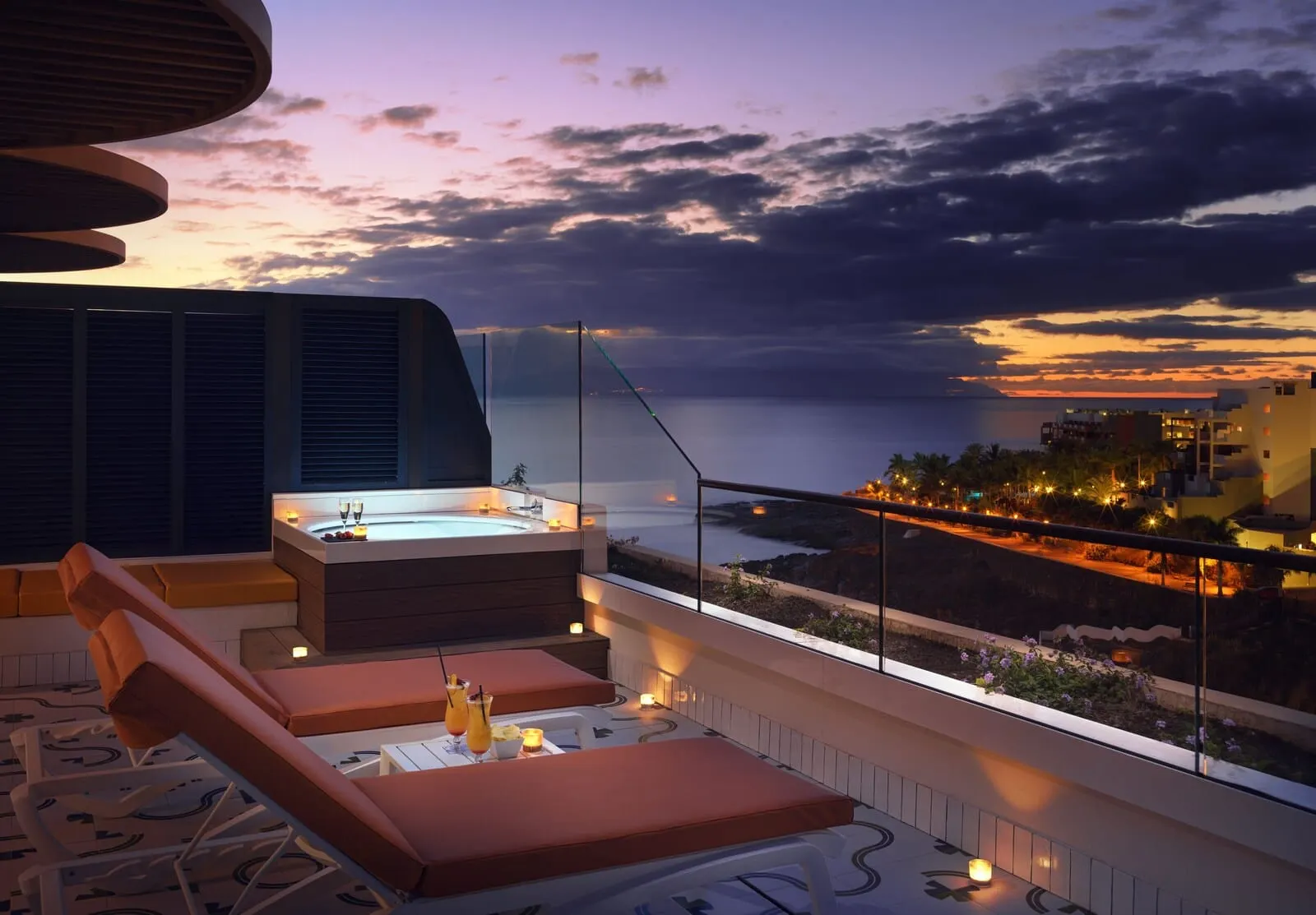 H10 Atlantic Sunset: A rooftop terrace with a hot tub, lounge chairs, and a view of the sea at sunset