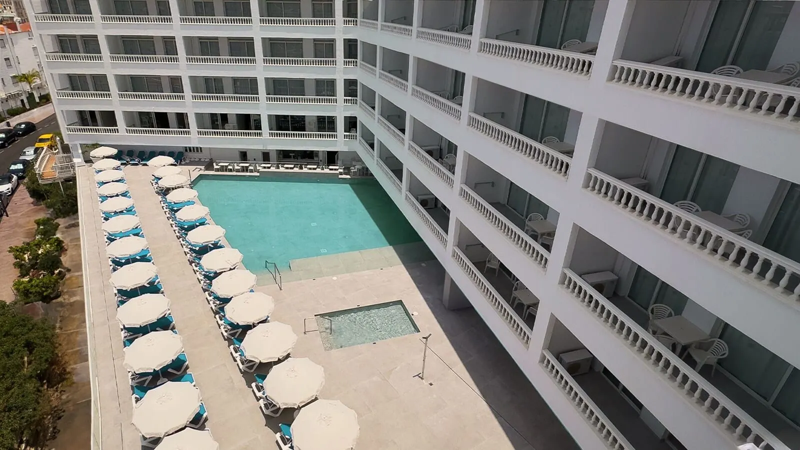 BlueSea Lagos de César: A multi-story hotel with a central swimming pool surrounded by rows of sun loungers