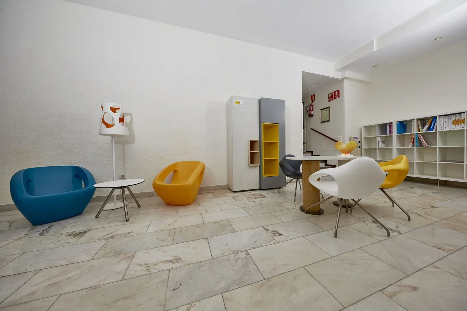 Coral Teide Mar: A modern, well-lit room with a blue and yellow chair, a white table, a bookshelf