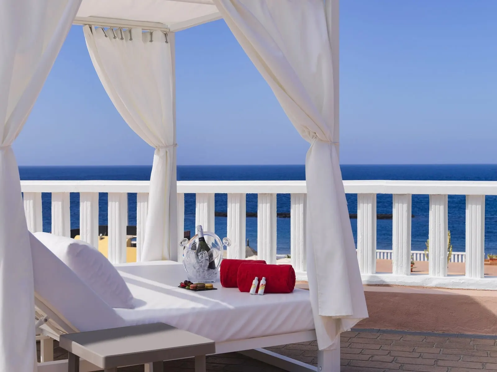 Sol Sun Beach Apartamentos: A white canopy bed with a view of the ocean, a table with a bottle and glasses