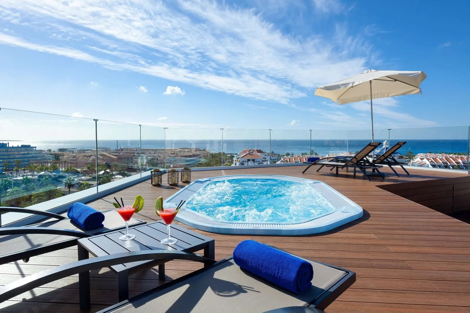 Best Tenerife: A rooftop pool area with a hot tub, lounge chairs, and a view of the ocean