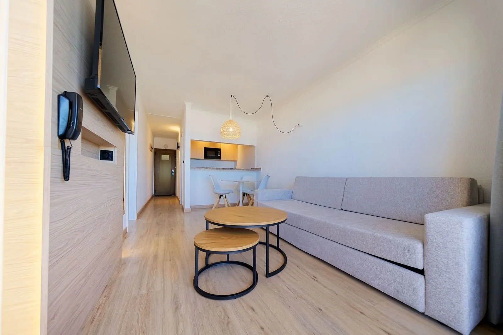 Servatur Caribe: A modern living room with a sofa, two wooden tables, a flat-screen TV, a phone