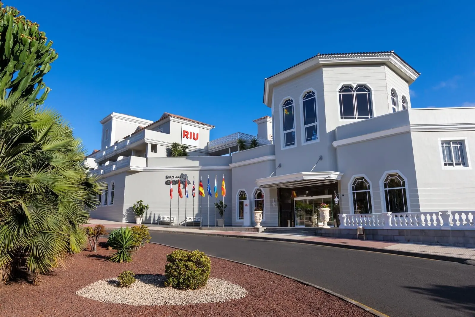 Hotel Riu Garoé: A hotel with a white facade, multiple flags